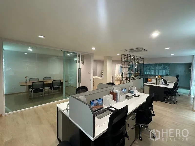 Warehouse for sale in Pathum Thani - Open-plan office with workstations, a glass meeting room and recessed lighting inside the warehouse complex.