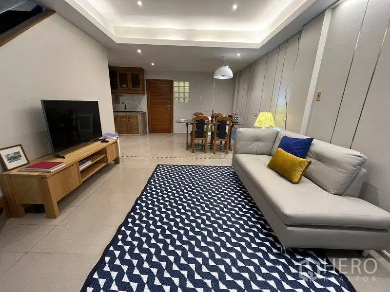 ทาวน์เฮาส์ for rent in Phra Khanong, Bangkok - พื้นที่นั่งเล่นแบบเปิดโล่ง มีโซฟา ชั้นทีวี ชุดทานอาหาร และพรมลาย.