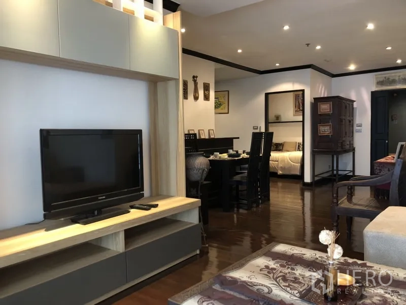 公寓 出租在Watthana, Bangkok - 客厅电视柜与起居区，旁边是餐桌和卧室入口。