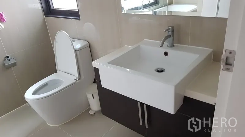 Condominium for rent in Ratchathewi, Bangkok - Contemporary bathroom featuring a square basin vanity, toilet and large mirror by a window.