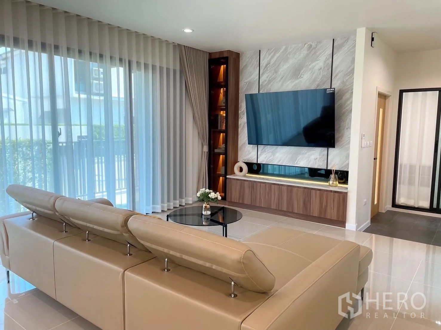 บ้านเดี่ยว for rent in Bang Phli, Samut Prakan - ห้องนั่งเล่นร่วมสมัย โซฟาหนังรูปตัวแอล ทีวีติดผนังหินอ่อน และผ้าม่านโปร่ง