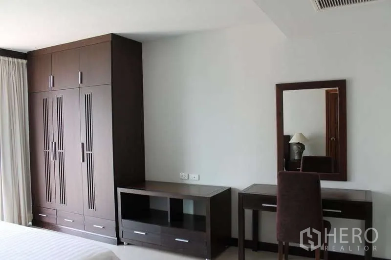 Condominium for rent in Sathon, Bangkok - Bedroom corner with large built-in wardrobe, dressing table, and TV console in dark wood.