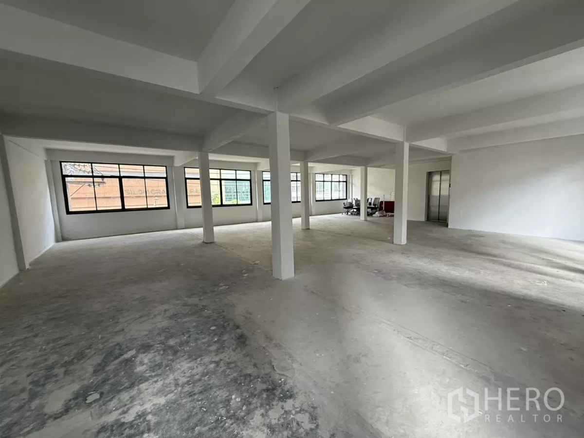 Office Space for rent in Bang Rak, Bangkok - Spacious unfurnished office area with rows of windows and lift access.