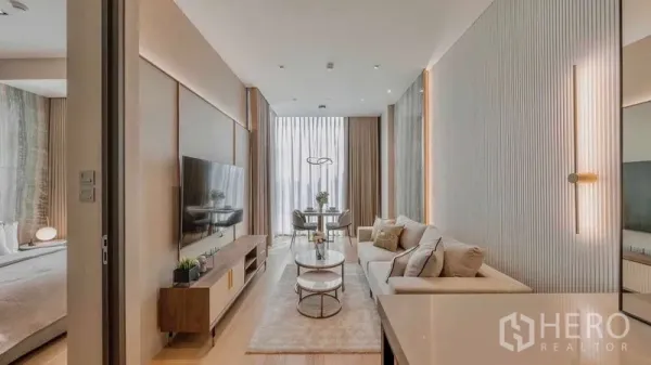Condominium for rent or sale in Pathum Wan, Bangkok - Long living space with sofa, media console and dining nook at full-height windows.