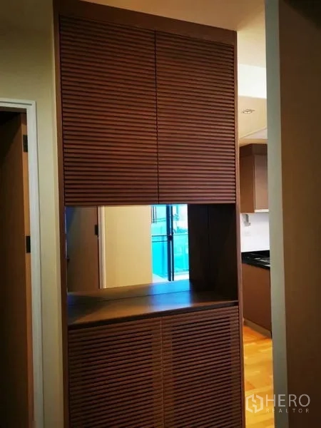 Condominium for sale in Khlong Toei, Bangkok - Hallway storage cabinet with slatted wooden doors facing the kitchen.