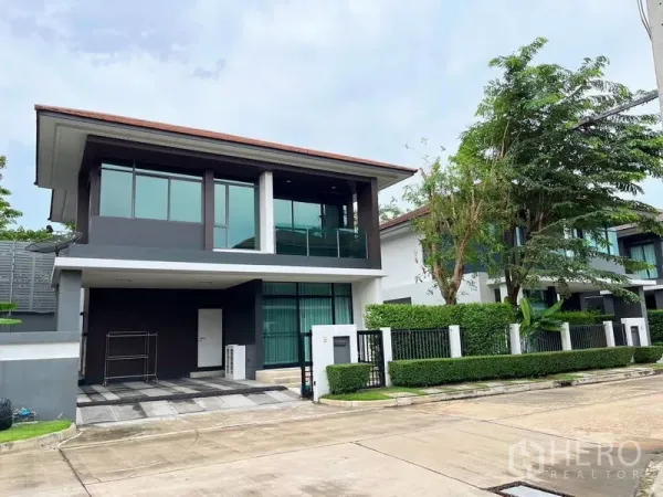 独立式住宅 出租在Bang Kapi, Bangkok - 两层现代独栋别墅外立面，车道与修剪整齐的绿篱