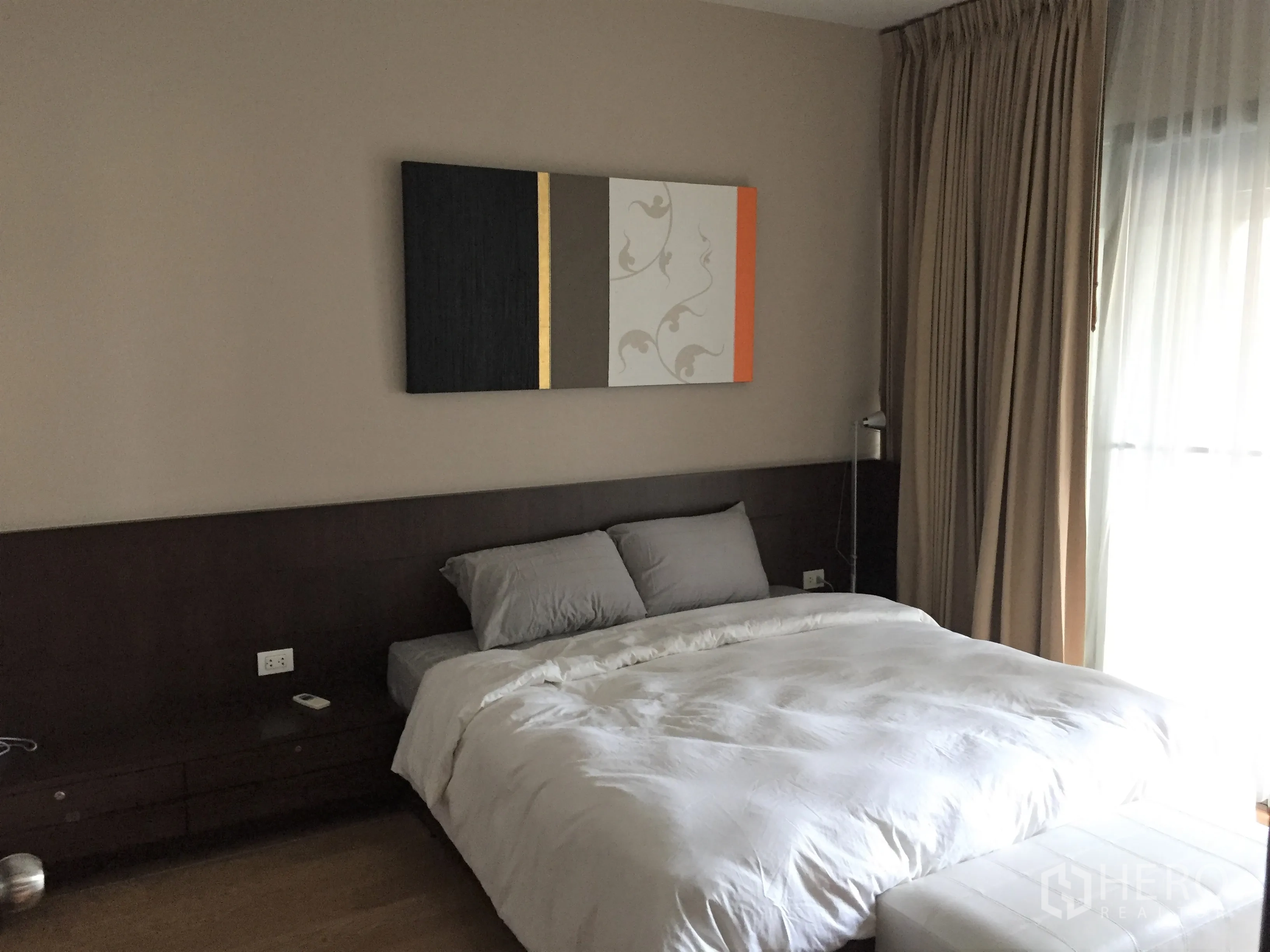公寓 出租在Watthana, Bangkok - 主卧配深色木质床头、装饰画与落地窗帘，光线柔和的曼谷瓦他那区公寓卧室。