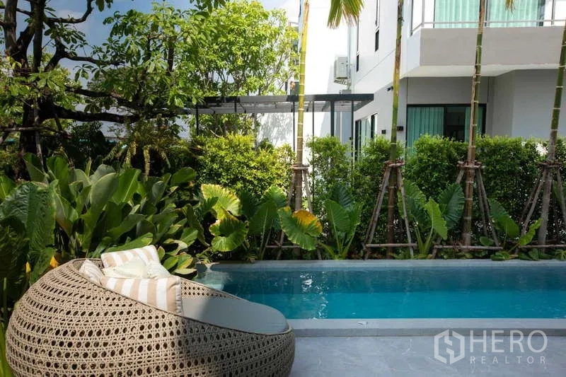 独立式住宅 出租或出售在Lat Krabang, Bangkok - 私家小泳池，周围热带绿植与编织躺床。