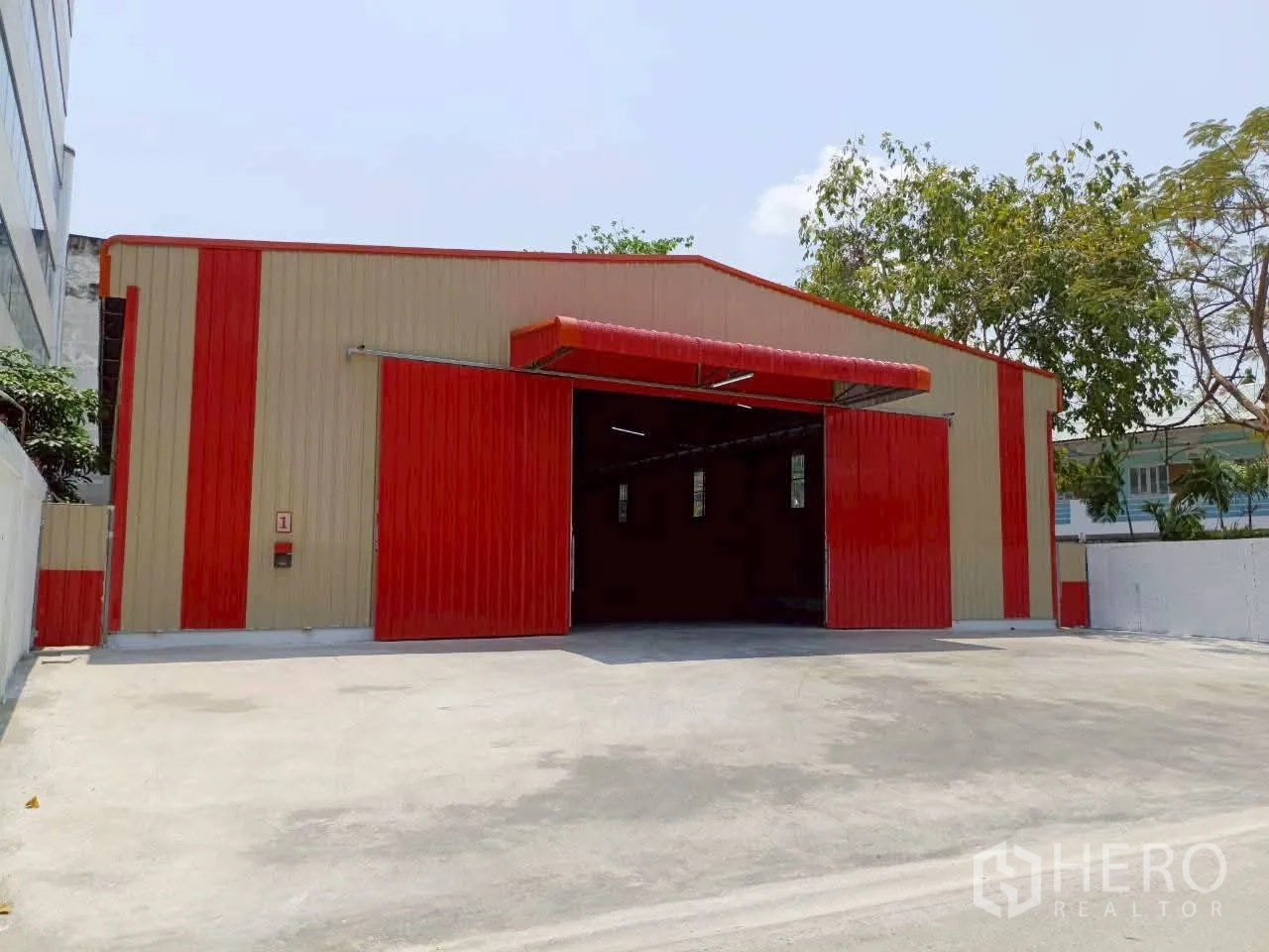 Warehouse for rent in Prawet, Bangkok - Warehouse exterior with large sliding doors and a paved forecourt for loading and parking.