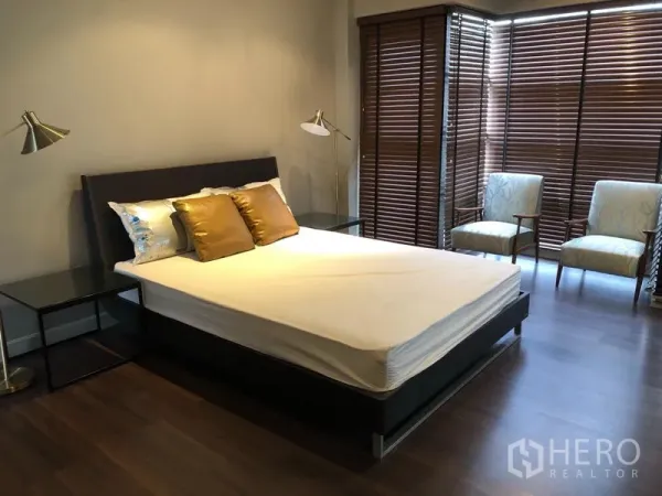 公寓 出租在Khlong Toei, Bangkok - 第二卧室设床与边几，转角窗配木百叶与休闲椅。