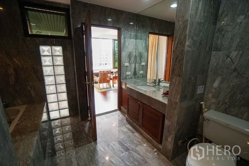 Apartment for rent in Watthana, Bangkok - Marble bathroom featuring a double vanity, bathtub, and glass-block divider.