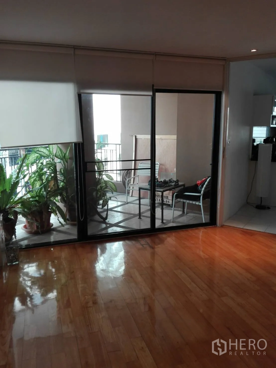Condominium for rent in Khlong Toei, Bangkok - Sliding glass doors to a covered balcony with potted plants and outdoor seating.