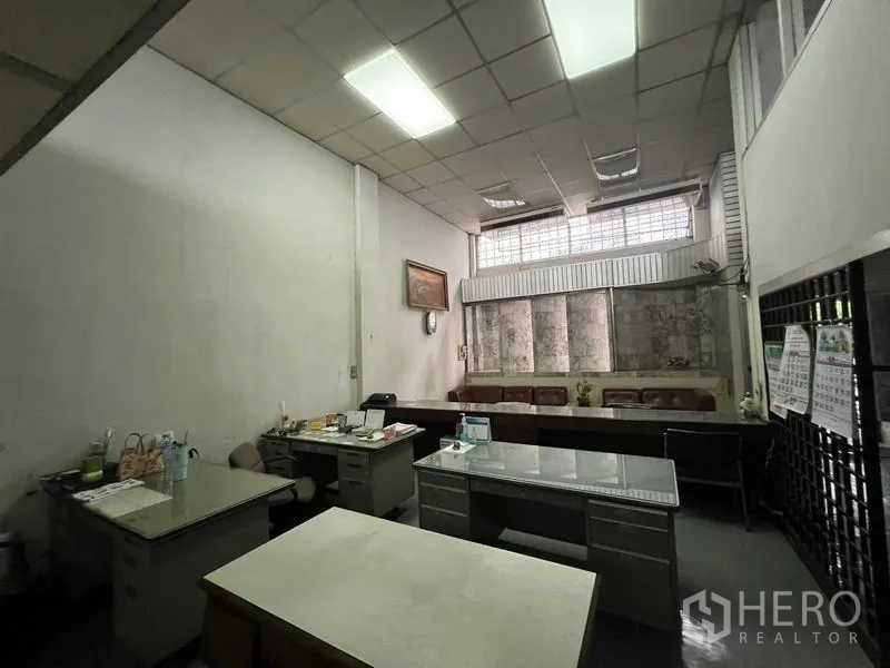 Shophouse for sale - Back office area with several desks and high windows for light.
