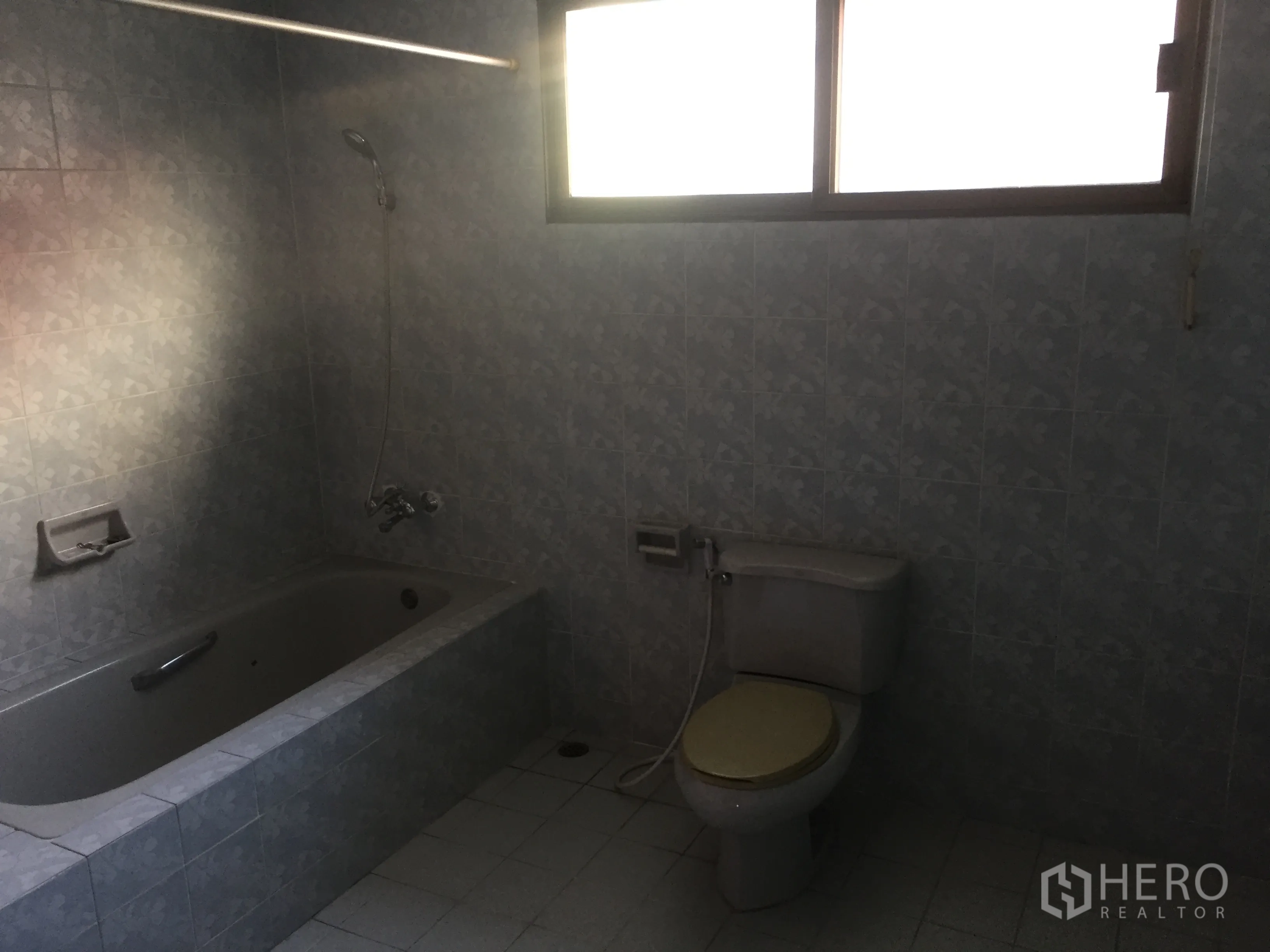 带办公室的家 出售在Watthana, Bangkok - 浴室设浴缸、坐便与手持花洒，蓝色花纹瓷砖和磨砂窗。