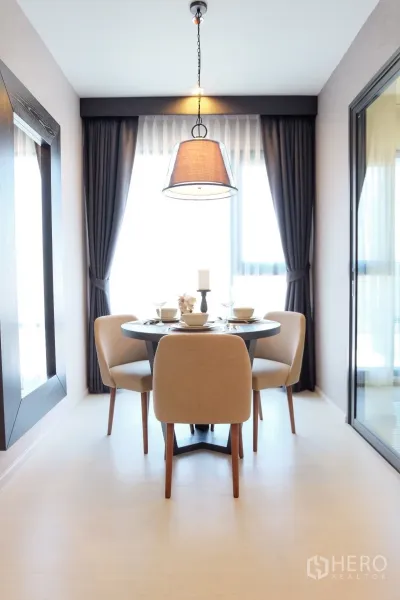 Condominium for rent in Khlong Toei, Bangkok - Bright dining nook with a round table for four under a pendant light and large windows.