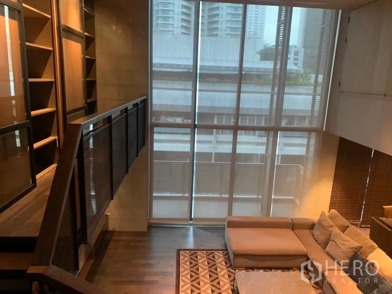 公寓 出租在Watthana, Bangkok - 楼梯与挑高落地窗，旁边是L形沙发。