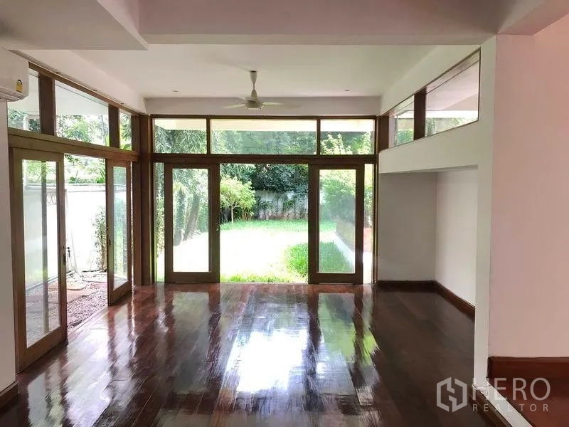 บ้าน ให้เช่าในWatthana, Bangkok - โถงนั่งเล่นเพดานสูง มองเห็นสนามหญ้าส่วนตัวผ่านประตูกระจก