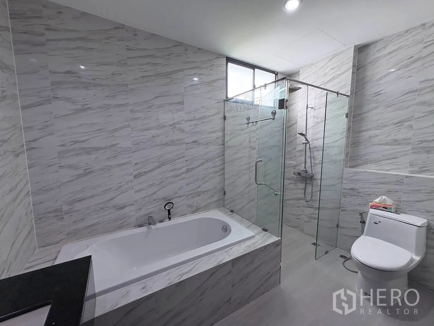独栋房屋 for rent in Saphan Sung, Bangkok - 现代浴室，仿大理石墙面，配浴缸、玻璃淋浴间与坐便器。