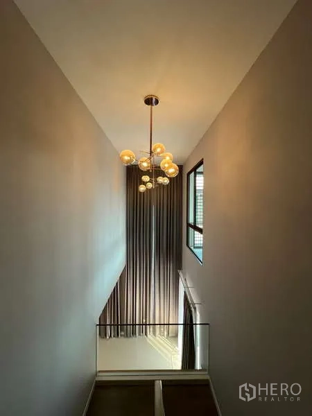 Detached House for rent in Bang Kapi, Bangkok - Stairwell with tall curtains and a contemporary chandelier.