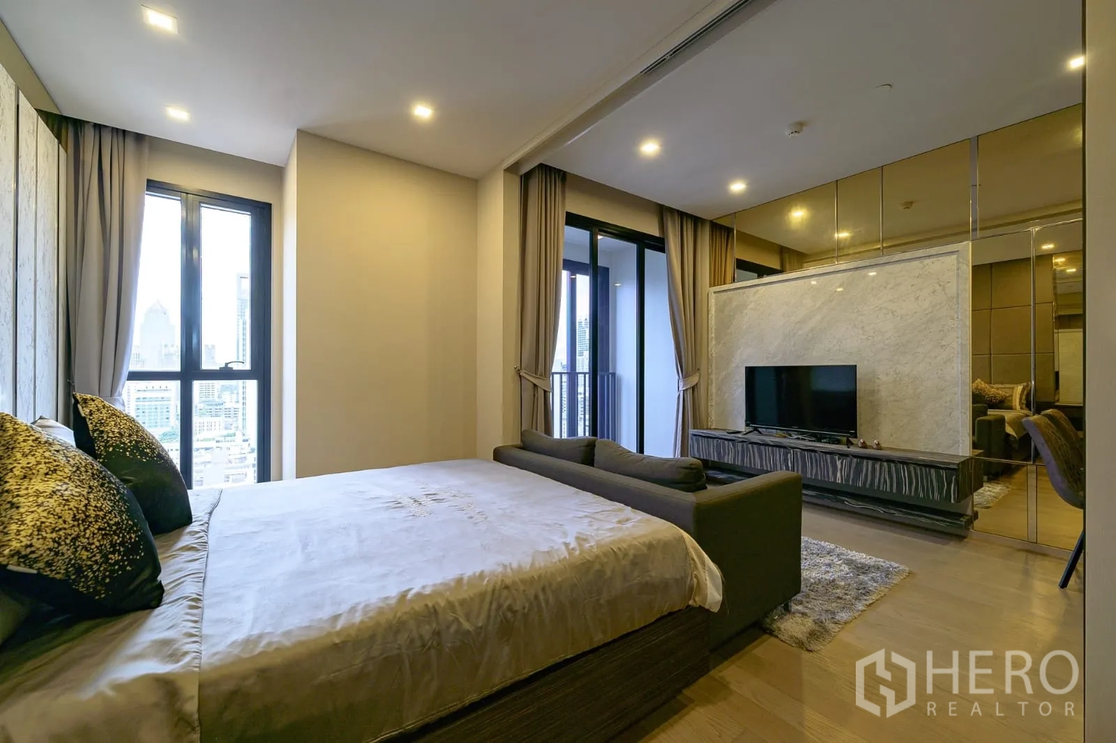 Condominium for rent in Watthana, Bangkok - Bedroom with bed, sofa, TV on a marble feature wall and access to the balcony.