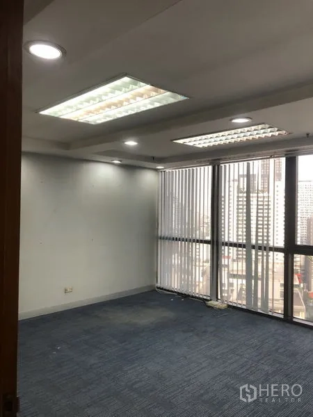 Office Space for rent - Bright open office area with large windows, vertical blinds, recessed lighting, and blue carpet tiles.