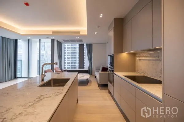 Condominium for rent in Pathum Wan, Bangkok - Sleek built-in kitchen with marble backsplash, induction hob, ovens and outlook to the living area.