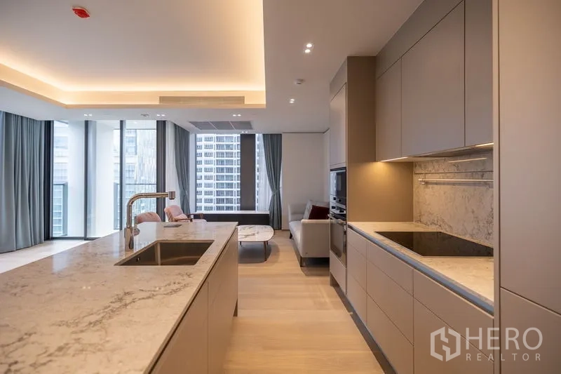 Condominium for rent in Pathum Wan, Bangkok - Sleek built-in kitchen with marble backsplash, induction hob, ovens and outlook to the living area.
