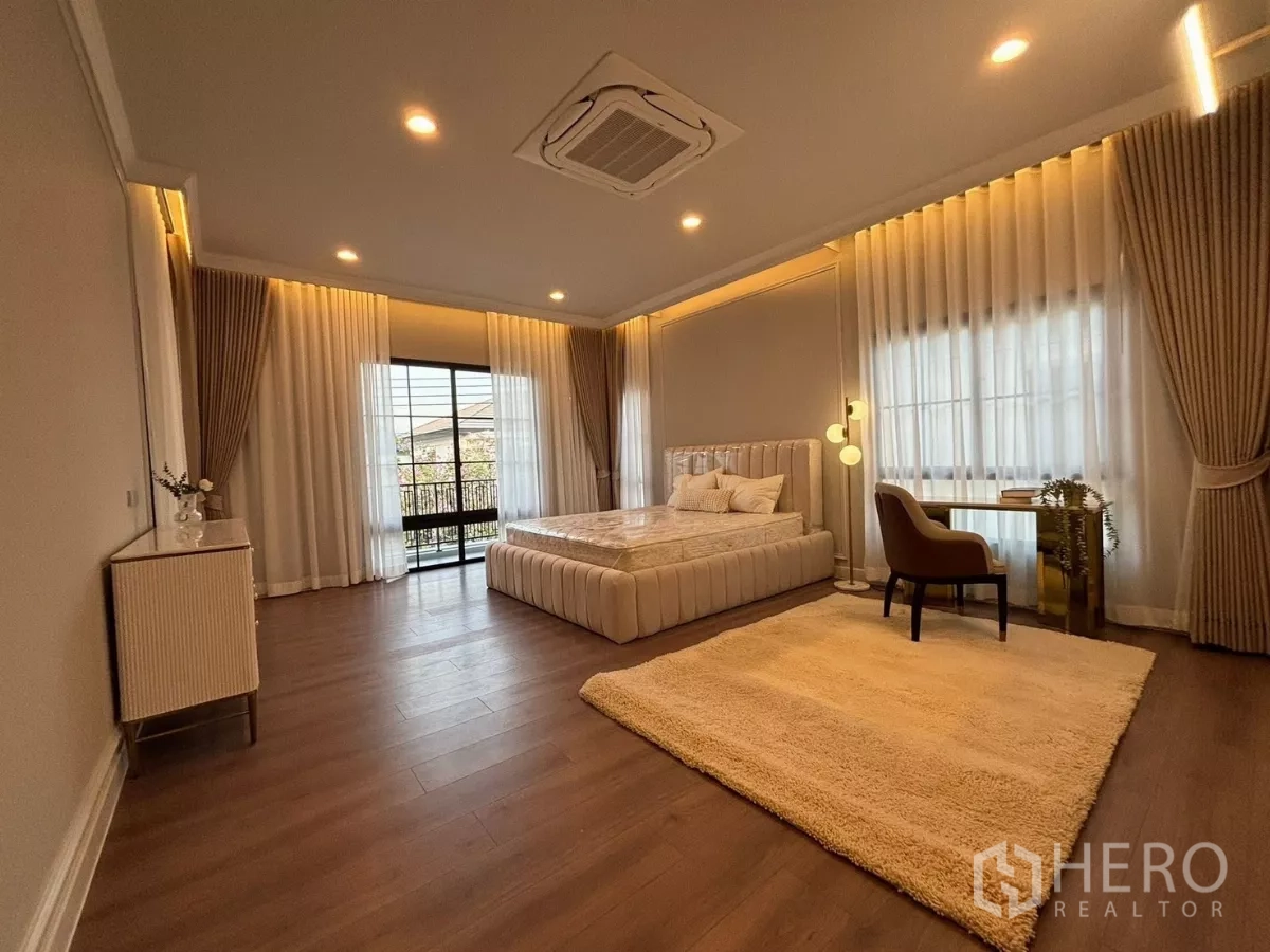 บ้าน ให้เช่าในBang Phli, Samut Prakan - ห้องนอนมาสเตอร์กว้าง มีประตูออกระเบียง พรมผืนใหญ่ และโต๊ะทำงาน.