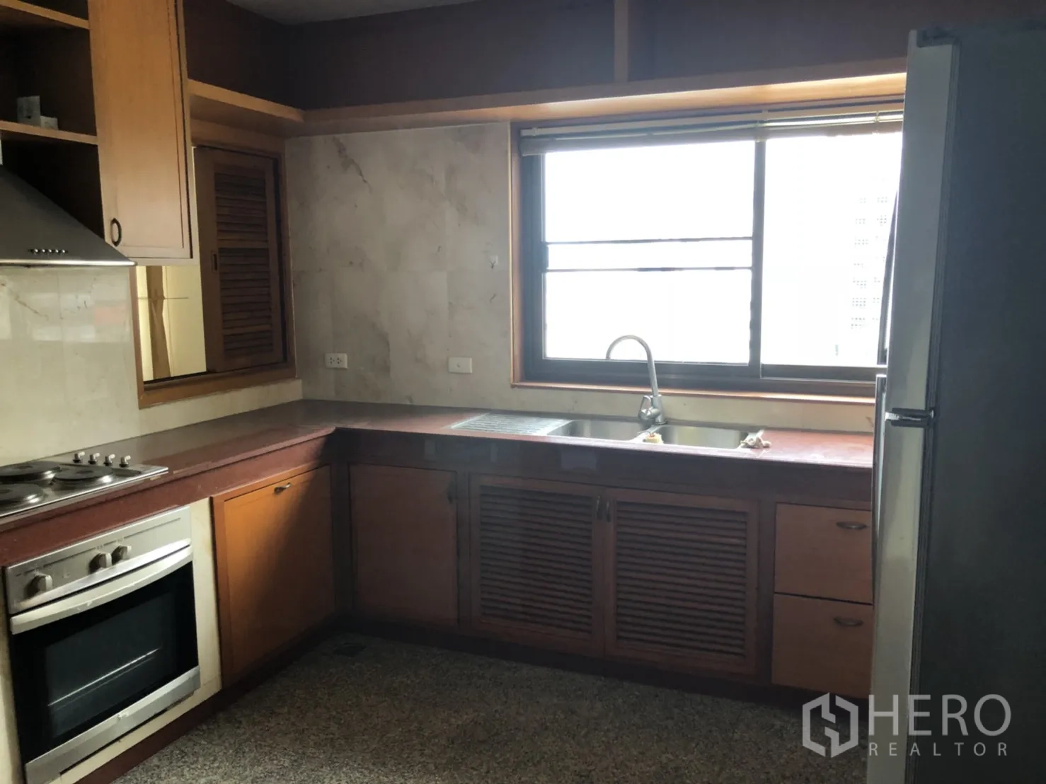 Apartment for rent in Bang Rak, Bangkok - Separate L-shaped kitchen with built-in oven, cooktop and hood, double sink, large window and fridge.