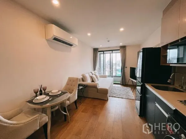 Condominium for rent in Ratchathewi, Bangkok - Living and dining area with sofa, bistro table set and sliding balcony doors.