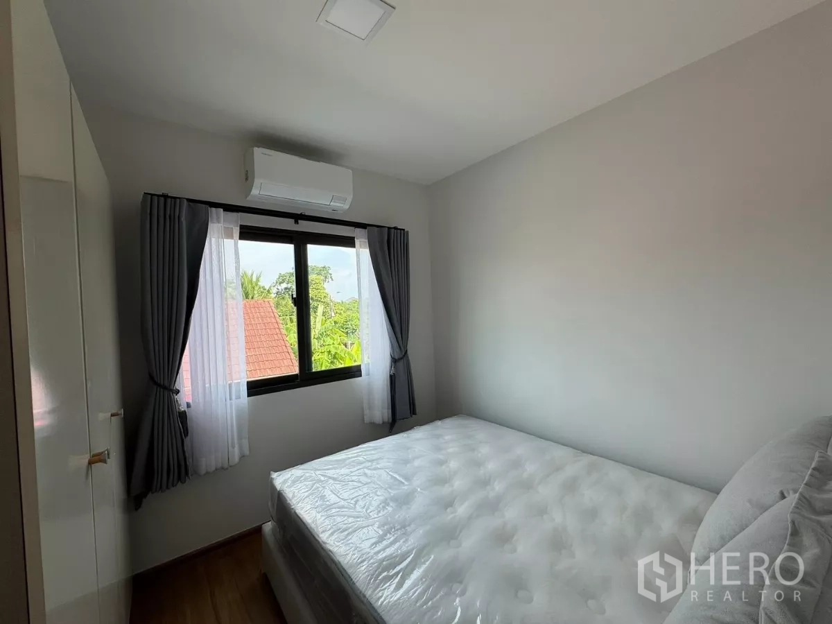 Townhouse for rent in Bang Phli, Samut Prakan - Guest bedroom with window, air conditioner and greenery view.