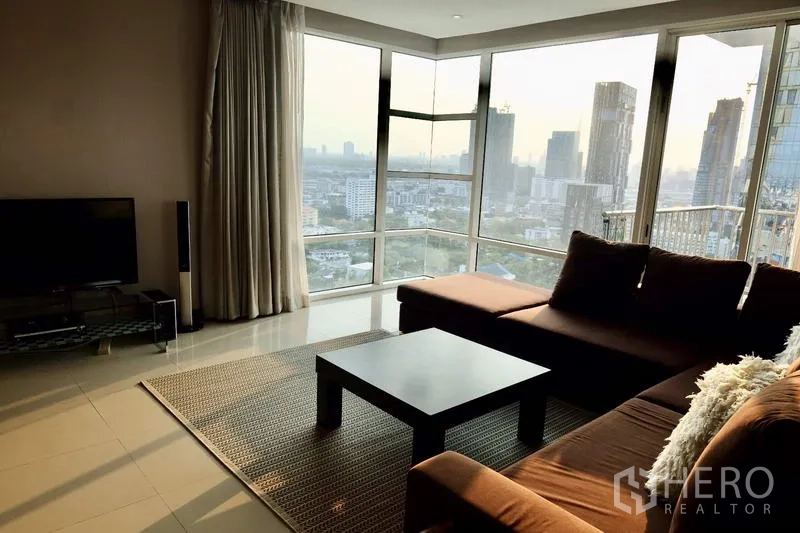 คอนโด ให้เช่าในWatthana, Bangkok - มุมห้องนั่งเล่นกระจกโค้งรอบ ชมวิวสกายไลน์กรุงเทพฯ ยามเย็น