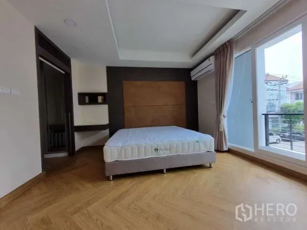 联排别墅 出租在Wang Thonglang, Bangkok - 宽敞主卧，落地阳台门、特色墙和人字木地板。