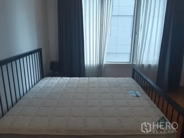 Condominium for rent in Khlong Toei, Bangkok - Master bedroom with large window, sheer and blackout curtains and a queen-size bed frame.