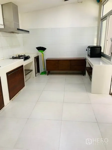 Townhouse for rent or sale in Huai Khwang, Bangkok - Simple kitchen with gas hob, range hood, white countertops and large windows