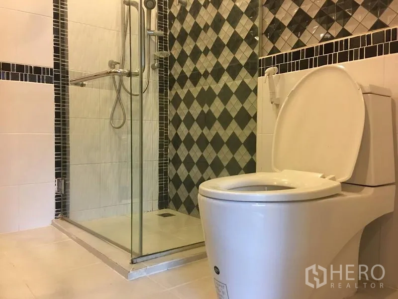 联排别墅 出租在Bang Rak, Bangkok - 现代浴室，玻璃淋浴间、手持花洒与坐便器，菱格瓷砖装饰。