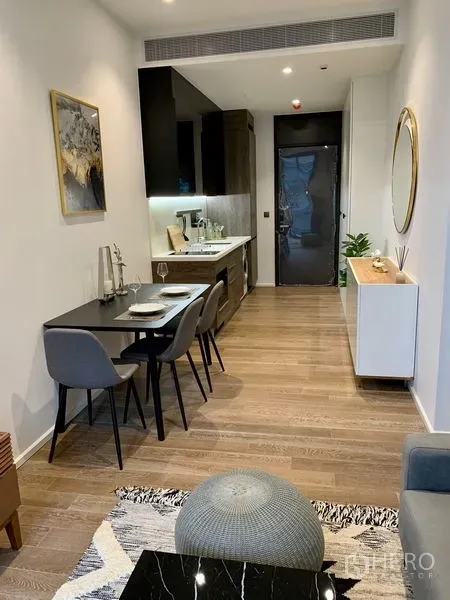 Condominium for rent in Pathum Wan, Bangkok - Open-plan living and dining area with kitchenette, wood floors, and modern lighting.