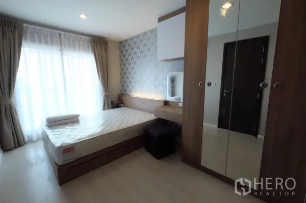 Condominium for rent in Sathon, Bangkok - Bedroom with floor-to-ceiling curtains, built-in headboard with soft lighting, mirrored wardrobe and queen bed.