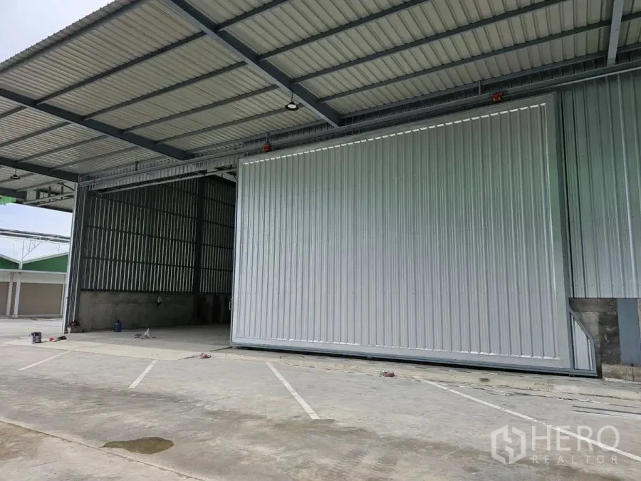 Warehouse for rent in Lam Luk Ka, Pathum Thani - Covered loading bay with a large sliding steel door at a modern warehouse in Lam Luk Ka.