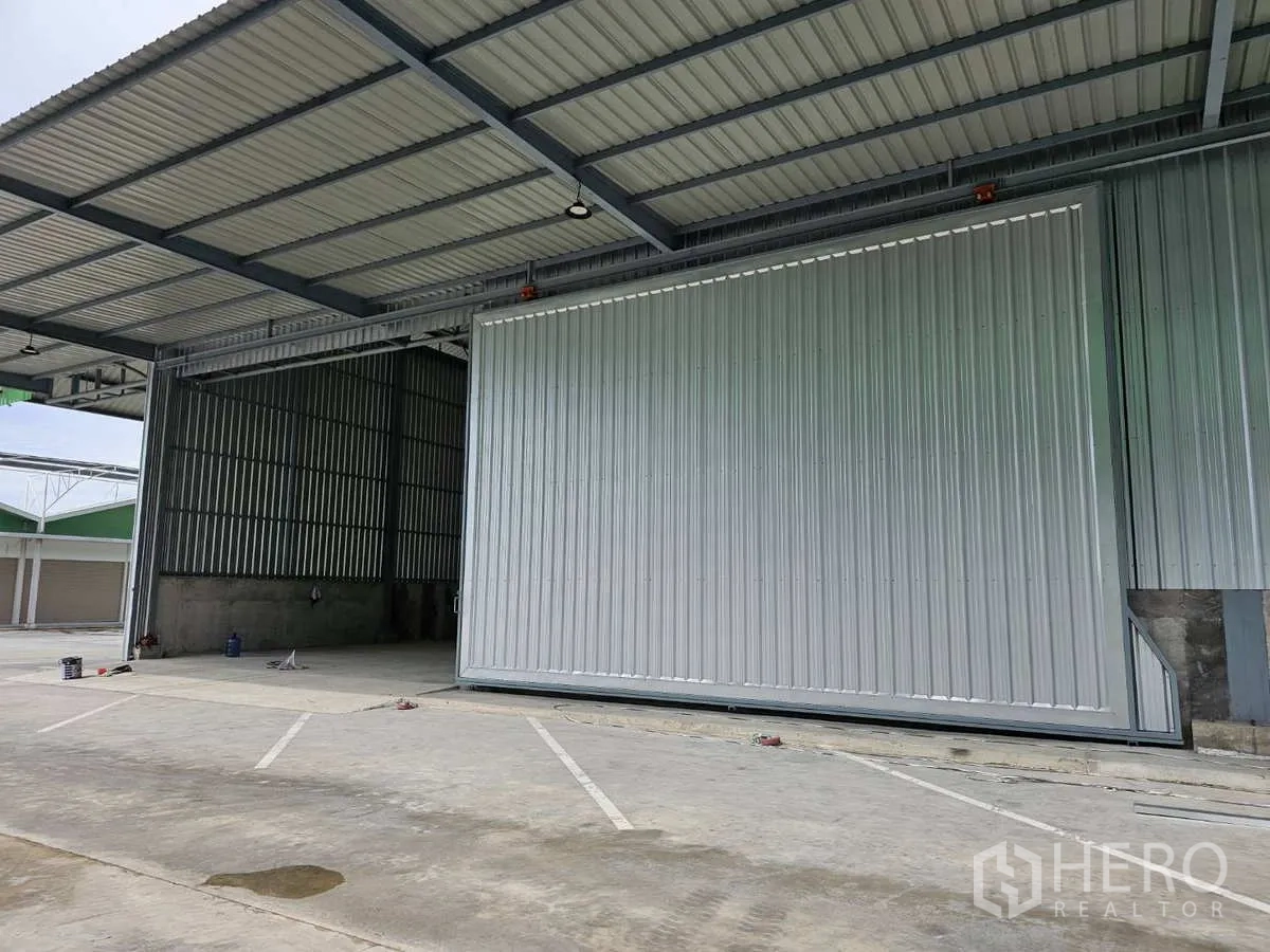 Warehouse for rent in Lam Luk Ka, Pathum Thani - Covered loading bay with a large sliding steel door at a modern warehouse in Lam Luk Ka.