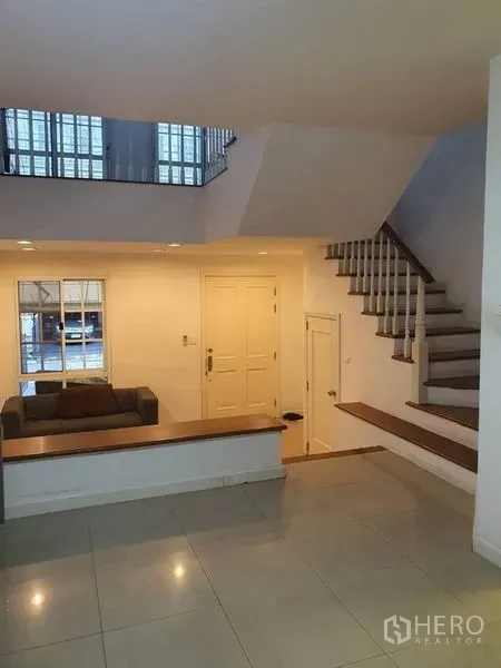 Townhouse for sale in Bang Kapi, Bangkok - Open-plan living area with staircase, white walls and recessed lighting.