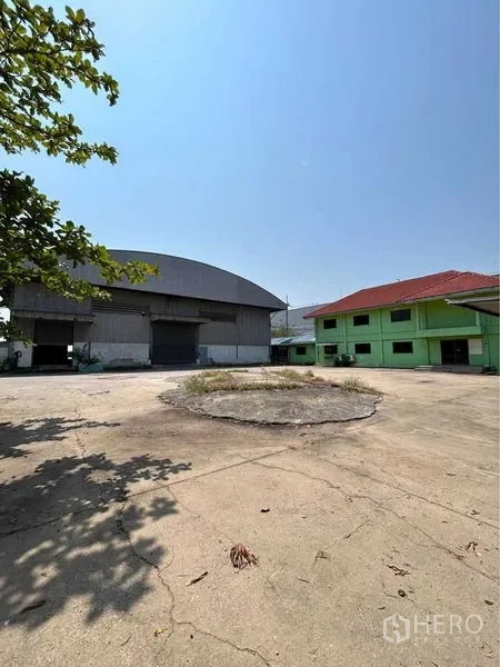 货栈 出租在Sam Phran, Nakhon Pathom - 仓库与绿色办公楼之间的宽阔混凝土场地，适合卡车回转。