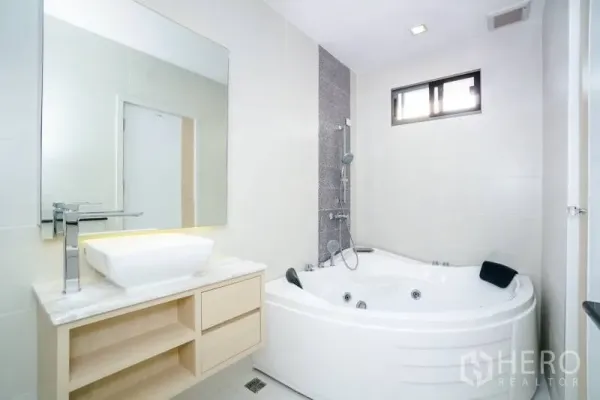 独立式住宅 出租或出售在Lat Krabang, Bangkok - 白色卫浴，设转角按摩浴缸、淋浴与大理石台面洗手台。