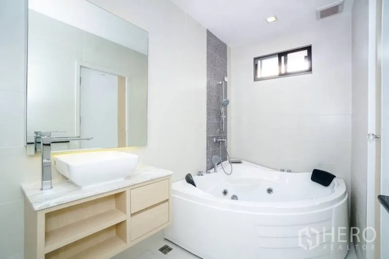 独立式住宅 出租或出售在Lat Krabang, Bangkok - 白色卫浴，设转角按摩浴缸、淋浴与大理石台面洗手台。