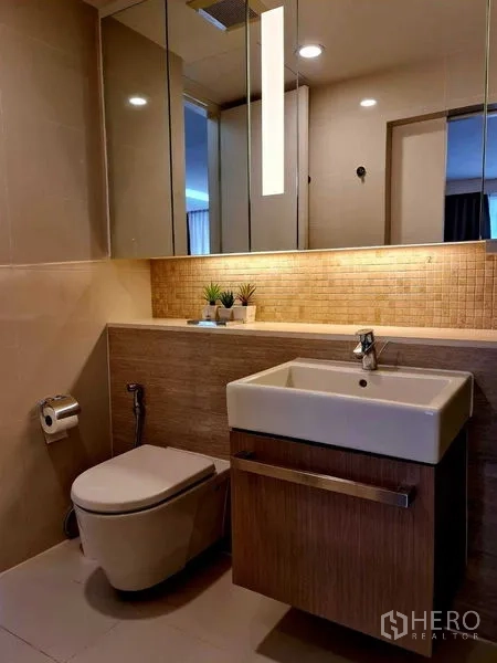 Condominium for rent in Watthana, Bangkok - Contemporary bathroom with square sink, wall mirror, toilet and accent tile lighting.
