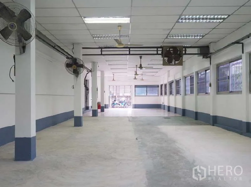 货栈 出租在Bang Kapi, Bangkok - 宽敞大厅，混凝土地面，壁挂风扇与带护栏的窗户，通风良好。