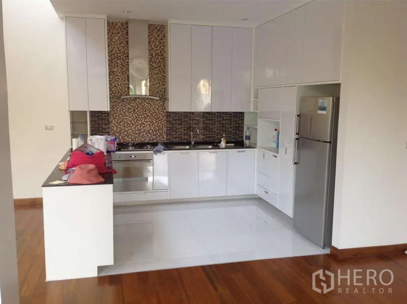 Detached House for rent in Lat Phrao, Bangkok - Bright modern kitchen with white cabinetry, mosaic backsplash, and built-in appliances.