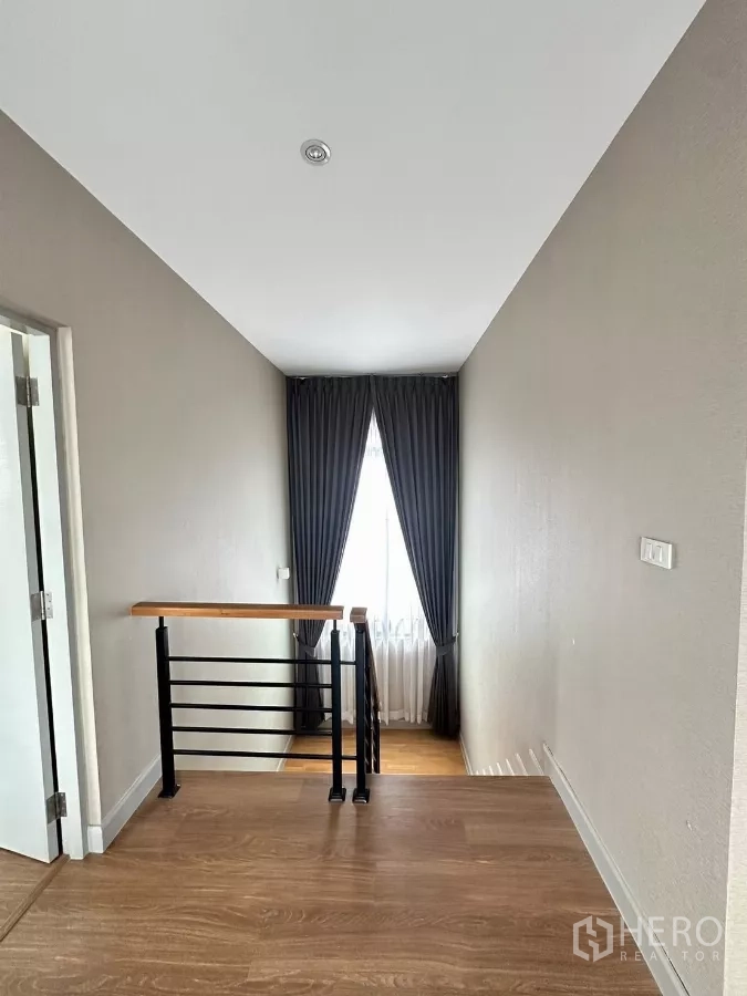 Detached House for rent in Saphan Sung, Bangkok - Upstairs landing with wood flooring, railing and curtained window.