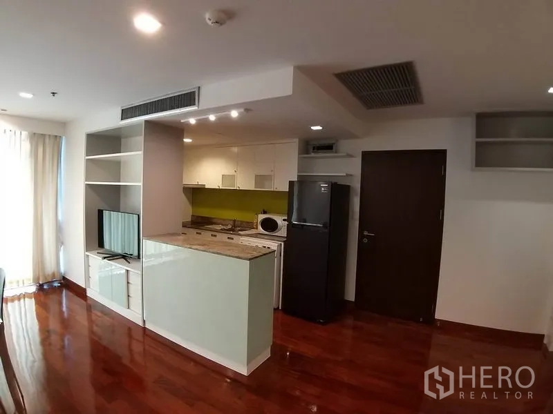 Condominium for rent or sale in Pathum Wan, Bangkok - Compact kitchen with a peninsula counter, open shelving and refrigerator in an open-plan layout.