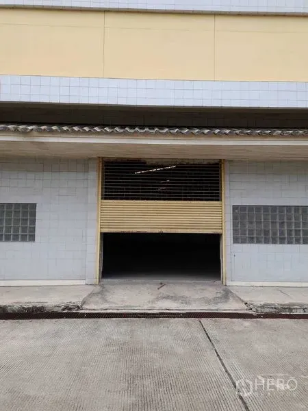 Warehouse for rent in Yan Nawa, Bangkok - Street-level view of the entrance showing rolling door and glass-block windows.